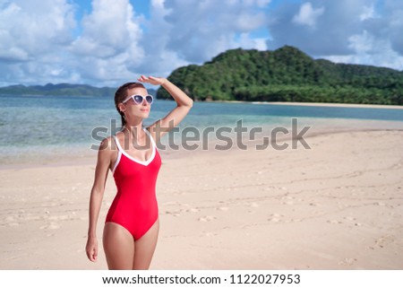 Enjoying suntan and vacation. Outdoor portrait of pretty young woman in red swimsuit on beautiful tropical beach.