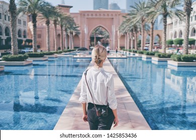 Enjoying travel in United Arabian Emirates. Young woman with camera walking on Dubai Downtown.