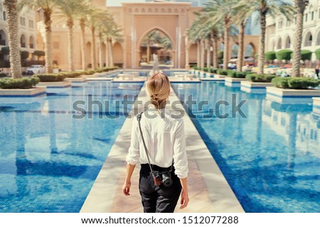 Enjoying travel in United Arabian Emirates. Young woman with camera walking on Dubai Downtown.