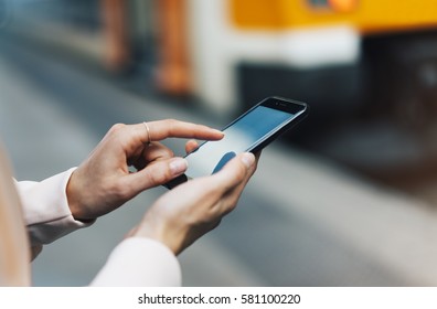 Enjoying travel. Young pretty woman waiting on the station platform with backpack on background train using smart phone. Tourist text message and plan route of railway, railroad transport concept - Shutterstock ID 581100220