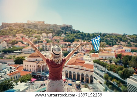 Enjoying vacation in Greece. Young traveling woman with national greek flag enjoying view of Athens city and Acropolis.