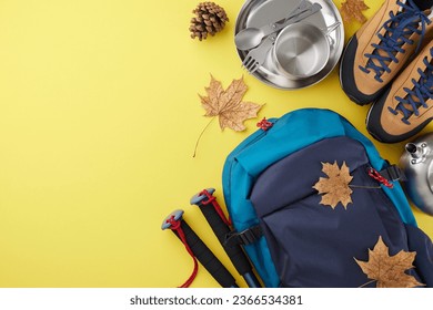 Enjoying the vibrant hues of autumn on a trek. Top view shot of metal utensils, boots, rucksack, trekking sticks, cones, autumn leaves on yellow background with promo area - Shutterstock ID 2366534381
