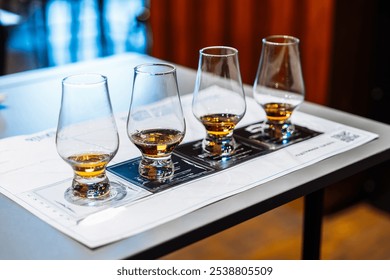 Enjoying whiskey tasting with four glasses and tasting notes on a table - Powered by Shutterstock