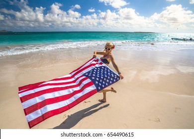 Enjoying woman celebrate independence day waving American flag in tropical Hawaiian beach. Lanikai Beach, east shore of Oahu in Hawaii, USA. Freedom and patriotic concept. Indipendence day.