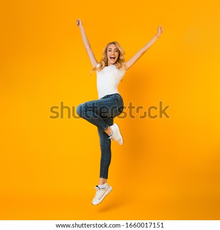 Enjoying youth. Overjoyed girl fooling and jumping on yellow studio background, crop