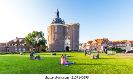 Enkhuizen, The Netherlands - July 20, 2021: People relaxing in park beside gate Drommedaris.in historic fishing village Enkhuizen North Holland in The Netherlands