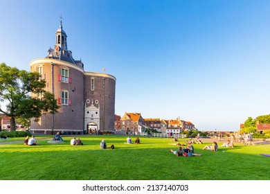 Enkhuizen, The Netherlands - July 20, 2021: People relaxing in park beside gate Drommedaris.in historic fishing village Enkhuizen North Holland in The Netherlands