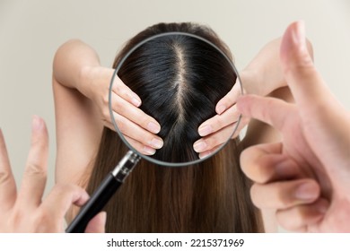 Enlarge a woman's scalp with a magnifying glass. - Shutterstock ID 2215371969