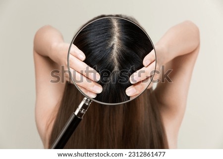Enlarge a woman's scalp with a magnifying glass.