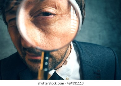 Enlarged eye of tax inspector and financial auditor looking through magnifying glass, inspecting offshore company financial papers, documents and reports. Professional financial forensics concept.
