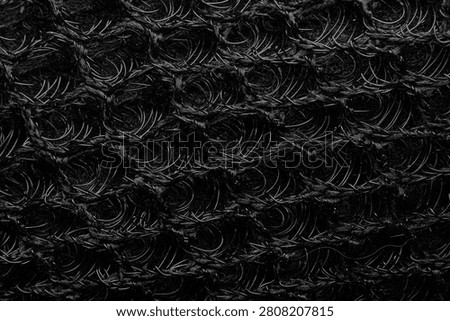 An enlarged image of the interwoven plastic mesh that forms the elastic loops used to make the motorcycle seat cover.