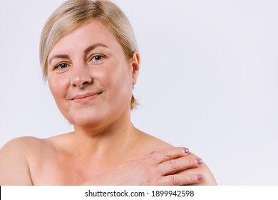 An enlarged photo of an older woman with a sweet smile and pure natural skin on a white background with side space.
