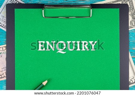 ENQUIRY - word (text) and money bills, dollars on a green background notepad, pencil, wooden table. Business concept: buy, sell, commerce (copy space).