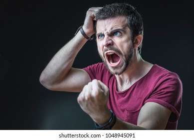 Enraged furious young man screaming in anger, pulling his hair out