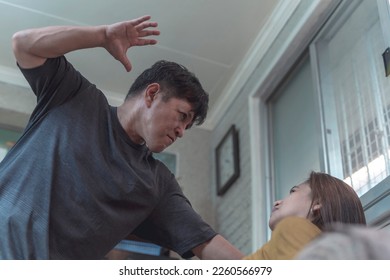 An enraged and sadistic man slaps his poor and defenseless wife cornered on the couch. Example of physical and psychological domestic abuse. - Shutterstock ID 2260566979