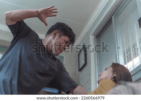An enraged and sadistic man slaps his poor and defenseless wife cornered on the couch. Example of physical and psychological domestic abuse. Stock photo © 
