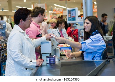 ENSCHEDE, THE NETHERLANDS - JUNE 27: A Female Cashier Of The Albert Heijn Supermarket Is Giving A Woman Her Receipt For The Products That She Just Bought And Paid, June 27, 2013 In The Netherlands.