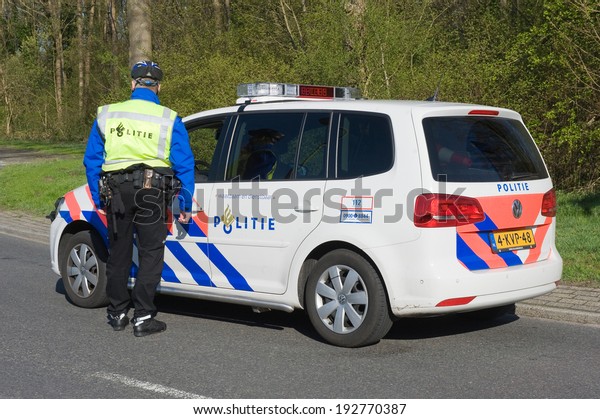 ENSCHEDE, NETHERLANDS - MARCH 25: A policeman\
is talking to a colleague in a police car during a surveillance on\
a street, march 25, 2014 in the\
Netherlands