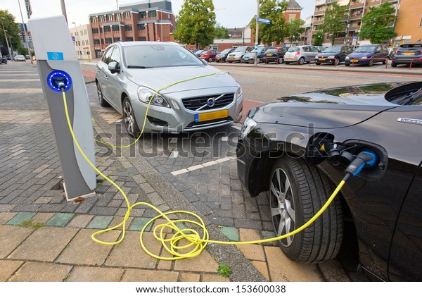 ENSCHEDE, The NETHERLANDS - SEPT 08: Two
electric cars are parked at a parking spot in the center of a town
while they are being recharged at a power station, September 08,
2013 in the
Netherlands.