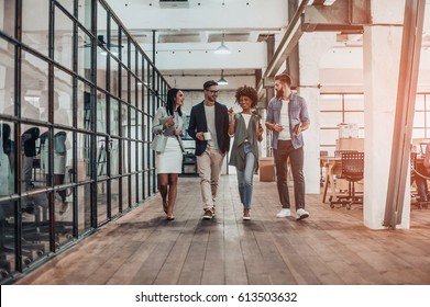 Ensuring success by working as a team. Full length of young modern people in smart casual wear having a discussion while walking through the office corridor