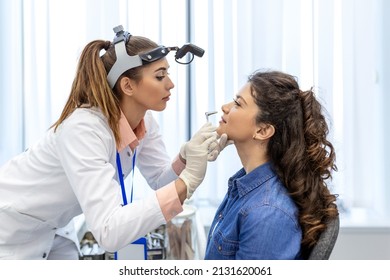 ENT clinic. Professional female doctor otorhinolaryngologist doing nose examination. Nasal congestion, sinusitis, allergy concept. Otolaryngologist examines woman's nose with nasal dilator.