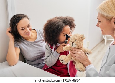 ENT Doctor Checking African Female Kid's Ear Using An Otoscope. Hearing Exam For Children