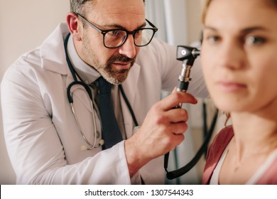 ENT Doctor Checking Ear With Otoscope Of Woman Patient At Hospital. Physician Examining Ear Of Female Patient With An Instrument.