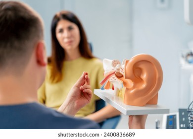 un médico de ENT consulta a un paciente en el consultorio de la clínica y le informa sobre las posibles consecuencias de la operación que muestra los canales de oído y nasal