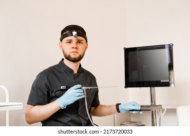 ENT Doctor Otolaryngologist With Endoscope In Hands. Prepearing For Endoscopy Procedure. Doctor With Headlight