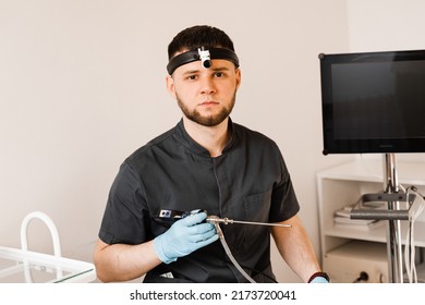 ENT Doctor Otolaryngologist With Endoscope In Hands. Prepearing For Endoscopy Procedure. Doctor With Headlight