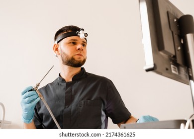 ENT Doctor Otolaryngologist With Endoscope In Hands. Prepearing For Endoscopy Procedure. Doctor With Headlight