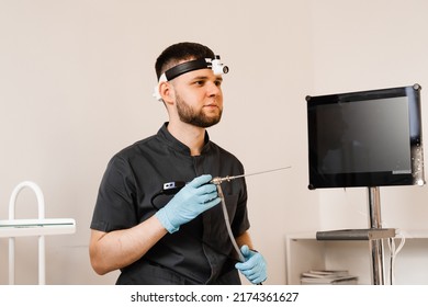 ENT Doctor Otolaryngologist With Endoscope In Hands. Prepearing For Endoscopy Procedure. Doctor With Headlight