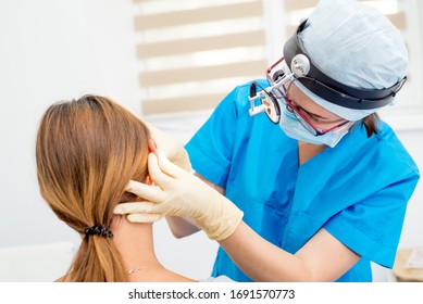 ENT Arzt mit Werkzeugen, Maske und Handschuhen untersucht die Ohren des Patienten. Otolaryngologin mit ihrWerkzeug