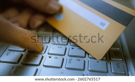 Entering CVVCVC code on a laptop keyboard with a credit card in hand, online payment security, cyber fraud risk, digital transactions, e-commerce safety