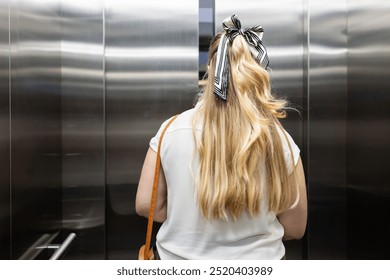 Entering elevator, woman with long blonde hair and striped bow in office building. Business, corporate, professional, workplace, style, fashion - Powered by Shutterstock