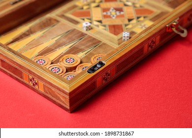 An entertaining game of backgammon on a red background. Checkers, cubes, handmade board