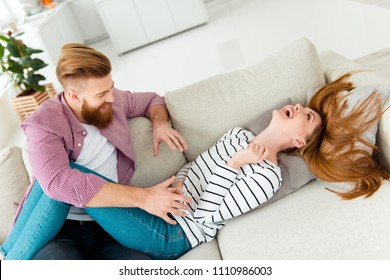 Entertainment fun-time wife husband living room spouse two partners concept. Cute funky lovely cheerful excited adorable pretty lady lying on divan covering closing body with hands afraid of tickle