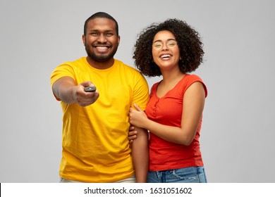 Entertainment And People Concept - Happy African American Couple With Tv Remote Control Over Grey Background