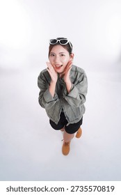 Enthralled Surprise: Captured from a low-angle perspective, a young woman beams with an expression of pure, unadulterated excitement, framed by trendy sunglasses perched atop her head.