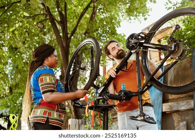 Enthusiastic active interracial couple doing yearly bike maintenance in yard for outdoor summer leisure activity. Healthy young male and female inspecting bicycle for damages. - Powered by Shutterstock