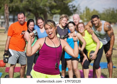 Enthusiastic  Bootcamp Fitness Instructor With Group Outdoors