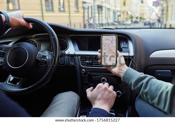 Enthusiastic couple using GPS navigation on the cell\
phone and searching for a suitable direction while sitting in\
modern car