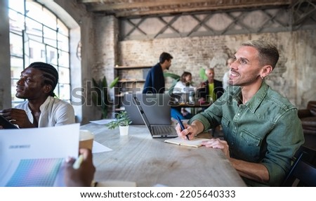 Enthusiastic creative man taking notes about a new marketing campaign - Portrait of happiness man smile while listening a reunion on the desk - Coworking and start up concept