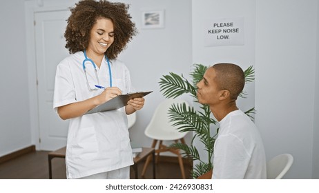 An enthusiastic doctor smiling, speaking, taking notes while having a medical consultation with a patient in the clinic's waiting room - Powered by Shutterstock