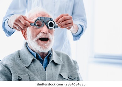 Enthusiastic elderly male patient wearing ophthalmic glasses for vision check, selecting eye sight lenses, spectacles. Ophthalmology occupation concept - Powered by Shutterstock