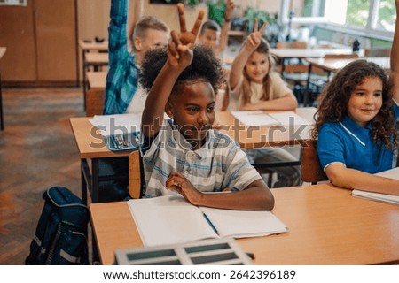 Enthusiastic elementary school students actively participate in class, raising hands and showing two fingers to answer teacher's questions, demonstrating engagement and eagerness to learn