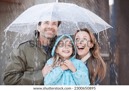 Enthusiastic family under umbrella in downpour