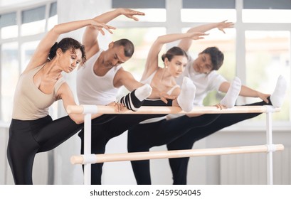 Enthusiastic female ballet student performing stretching exercises at barre to warm up during preparation to group rehearsal in spacious sunlit dance studio.. - Powered by Shutterstock
