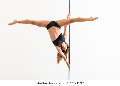 Enthusiastic female pole dancer with legs apart training over white background - Powered by Shutterstock