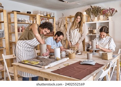 Enthusiastic group of four shaping clay in a well-lit pottery studio filled with shelves and tools. - Powered by Shutterstock